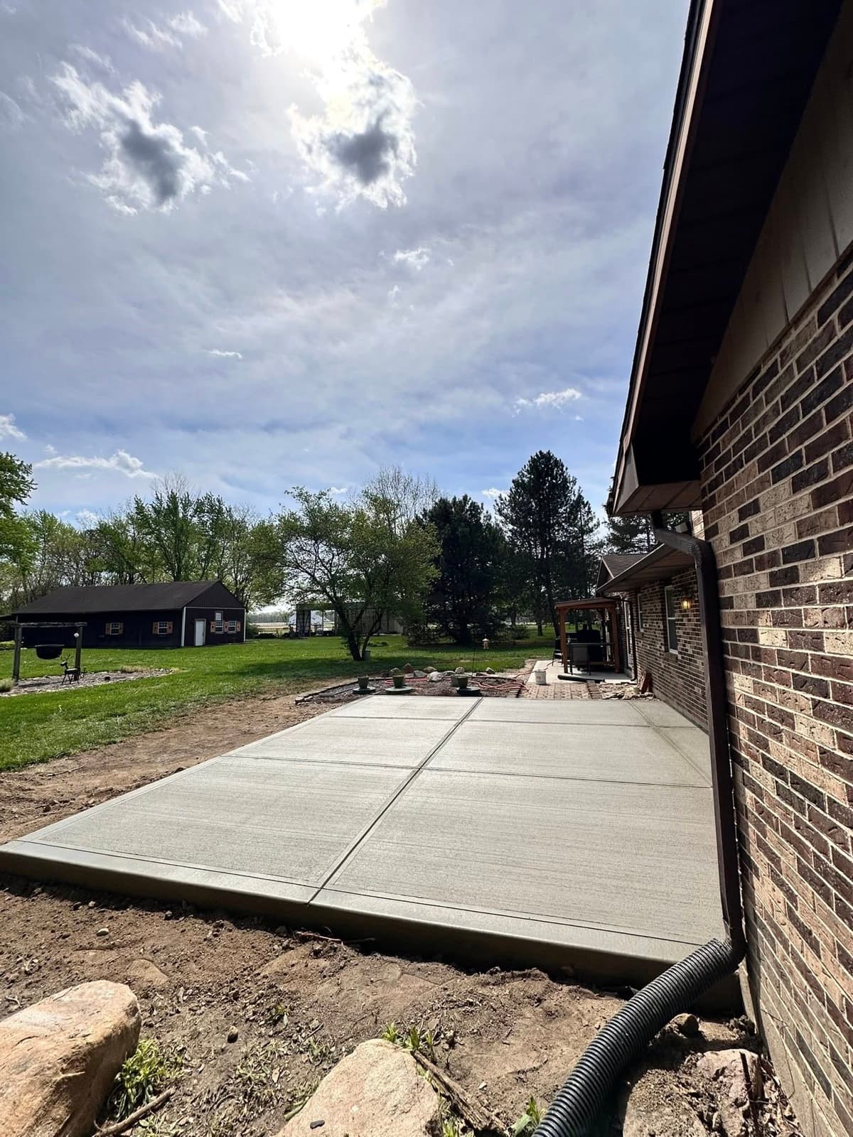 Backyard concrete patio at a brick home under a sunburst sky