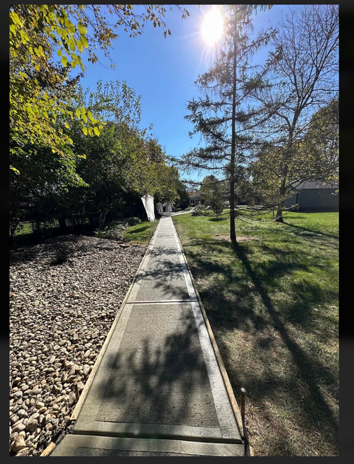 Long broom-finish concrete walkway through a sunlit Ohio yard