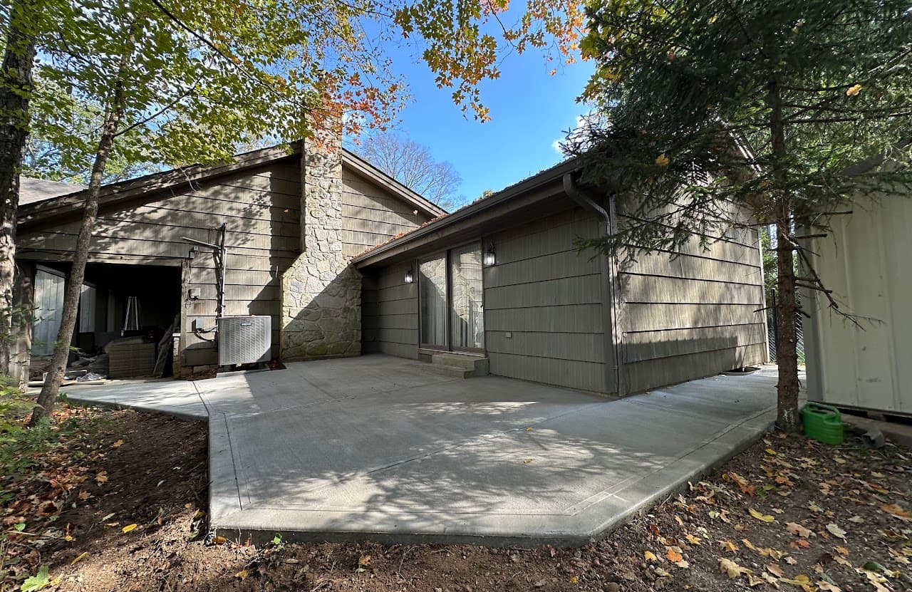 Mid-century home with stone chimney and a fresh broom-finish concrete patio in autumn