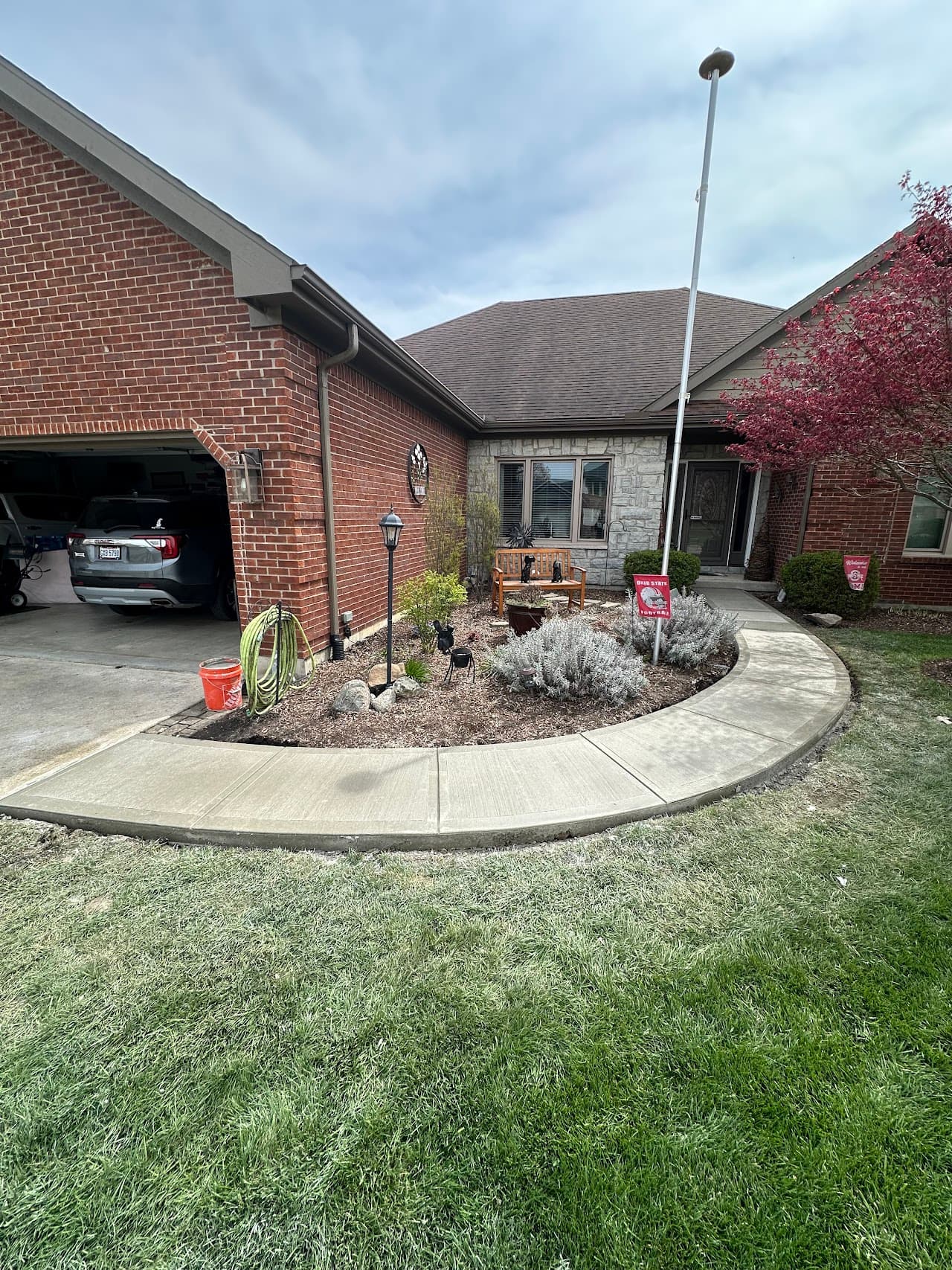 Sweeping curved sidewalk wrapping a landscaped bed at a brick ranch home