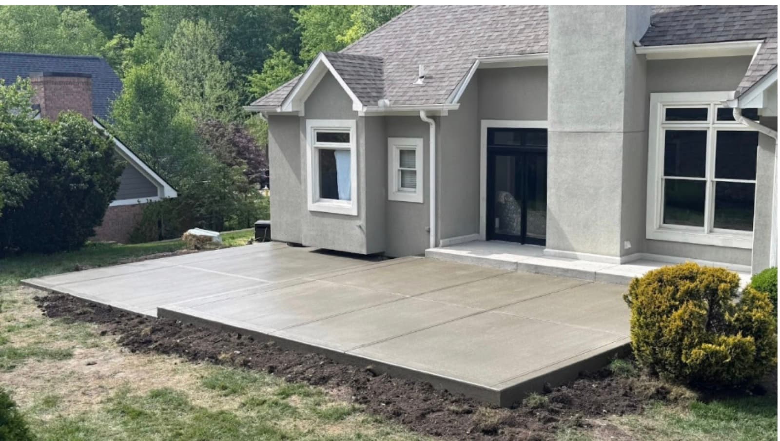 Fresh broom-finish concrete patio behind a gray stucco home