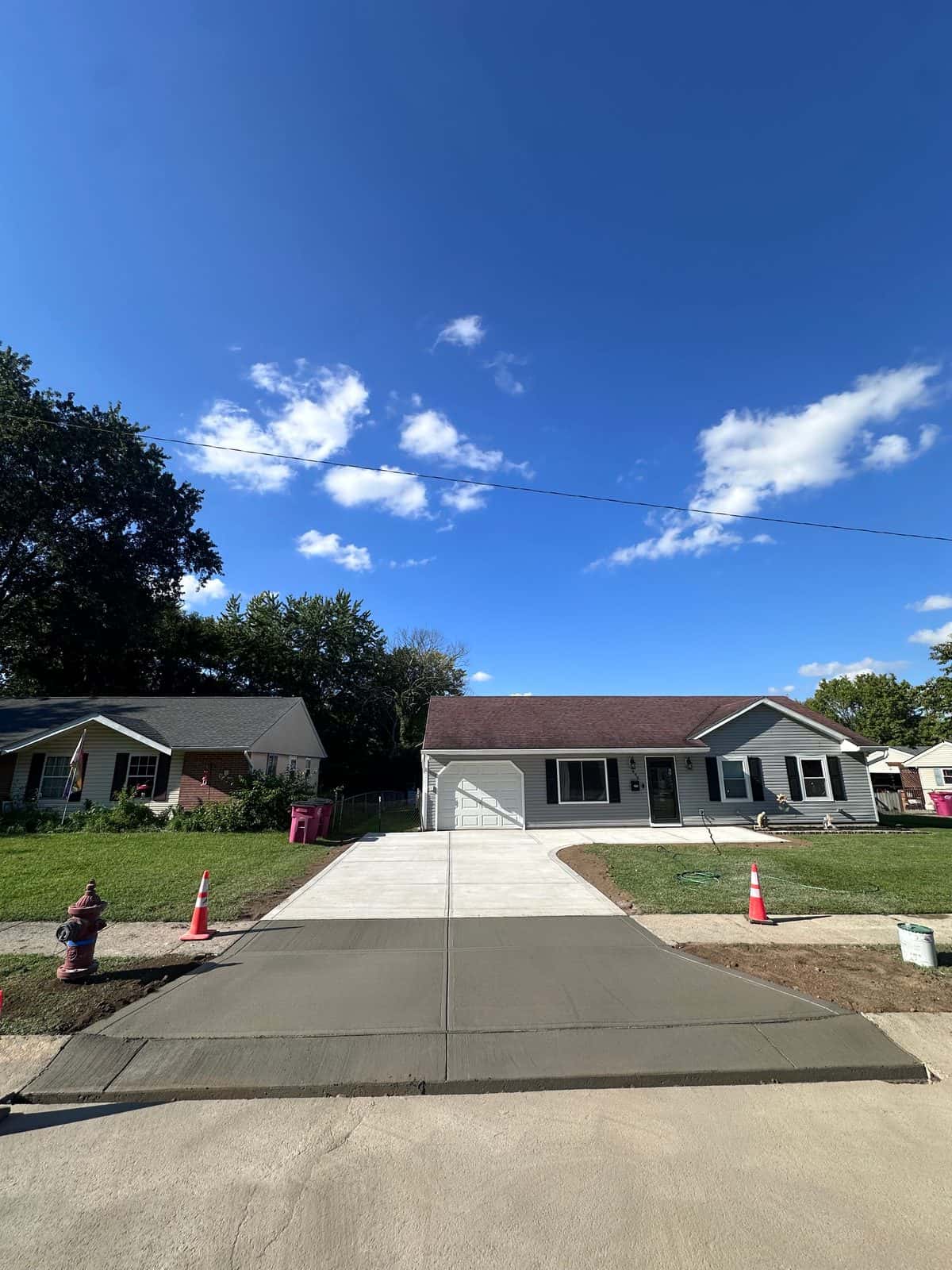 New concrete driveway and street apron at a ranch home with an attached garage