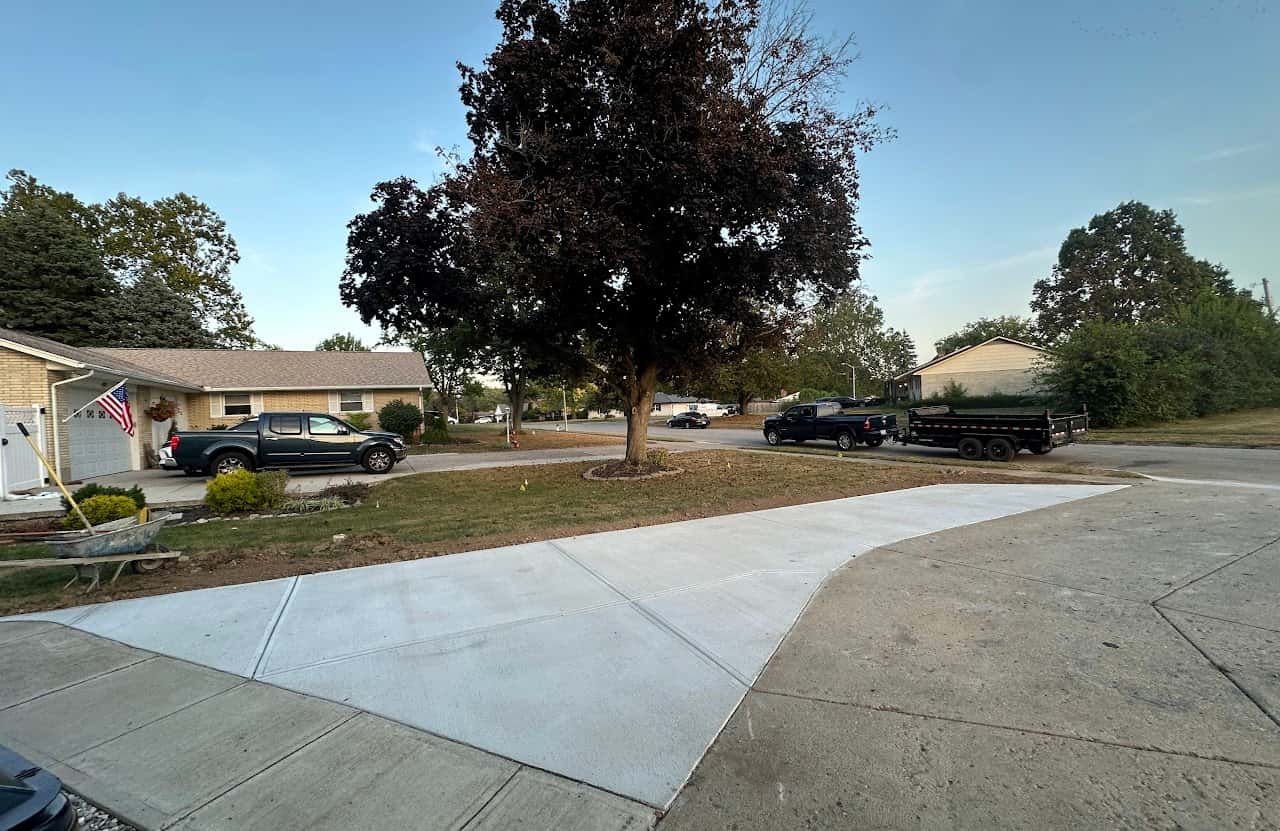 Concrete driveway extension at a ranch home with American flag and crew truck