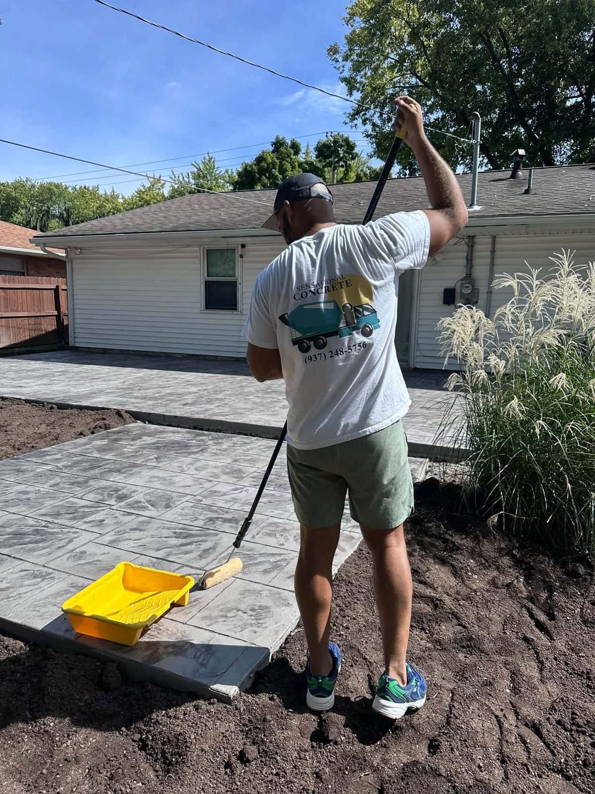 Sealing a freshly stamped concrete patio behind a ranch home